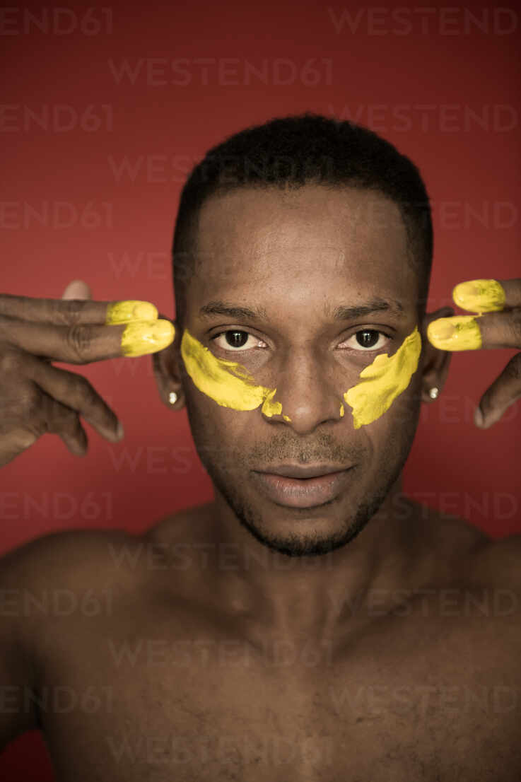 Headshot of adult African American man with yellow smears of paint