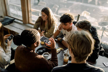 Hohe Winkel Ansicht der Teenager-Mädchen fotografieren Kaffee beim Sitzen mit Freunden in Cafe - MASF18651