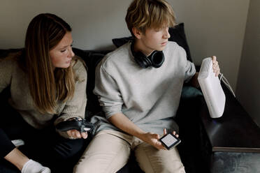 Jugendlicher überprüft Wi-Fi-Router, während er mit einem Freund zu Hause auf dem Sofa sitzt - MASF18669