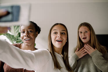 Smiling teenage girls taking selfie with mobile phone at home - MASF18671