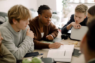Mädchen und Jungen im Teenageralter lernen zusammen am Tisch im Wohnzimmer - MASF18677