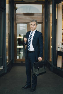 Porträt eines Geschäftsmannes mit Tasche vor einem Geschäft in der Stadt - MASF18730