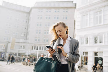 Worried entrepreneur using mobile phone while standing in city - MASF18775