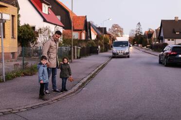 Vater mit Kindern auf dem Gehweg im Herbst stehend - MASF18825