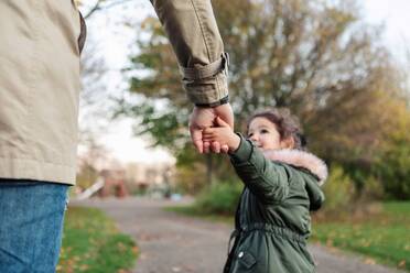 Daughter pulling father while holding hands in park during autumn - MASF18828