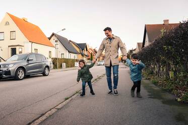 Lächelnder Vater mit Kindern auf dem Gehweg im Herbst - MASF18834