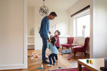 Verspielte Kinder im Gespräch mit ihrem Vater, während sie zu Hause stehen - MASF18838