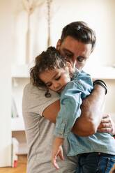 Vater umarmt traurige Tochter, während er zu Hause steht - MASF18850