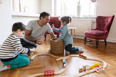 Verspielte Tochter bindet sich an ihren Vater, während ihr Bruder im Wohnzimmer spielt - MASF18855