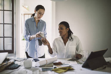 Designerinnen diskutieren über Stoffmuster bei der Arbeit am Tisch im Heimbüro - MASF18870