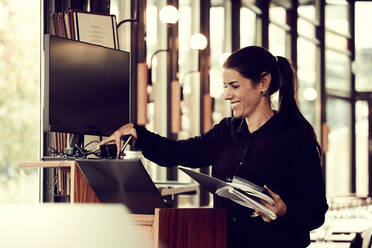 Lächelnder Besitzer, der einen Computerbildschirm in einem Café einstellt - MASF18927