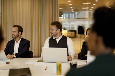 Männliche und weibliche Geschäftsleute mit Laptop in einer Besprechung im Büro - MASF18956