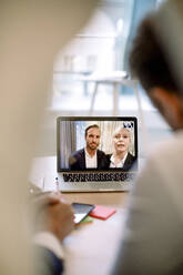 Videoanrufe von Kollegen über Laptop mit Geschäftsleuten im Büro - MASF18965