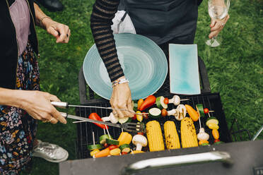 Frauen beim Grillen von Gemüse auf einer Gartenparty aus einem hohen Winkel - MASF19006