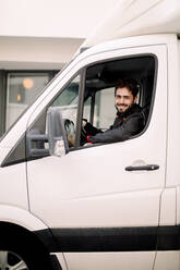 Porträt eines lächelnden jungen Mannes, der einen Lastwagen fährt - MASF19051