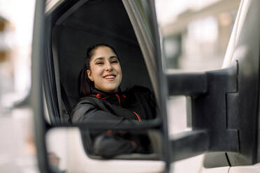 Porträt einer lächelnden jungen Frau, die einen Lastwagen fährt - MASF19054