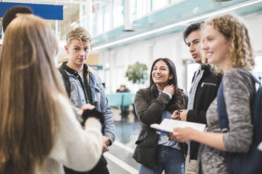 Junge männliche und weibliche Studenten unterhalten sich in der Cafeteria einer Universität - MASF19092