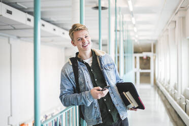 Porträt eines glücklichen jungen männlichen Studenten im Korridor einer Universität - MASF19096