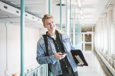 Portrait of happy young male student in corridor of university - MASF19096