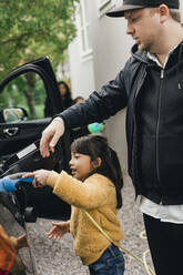 Mädchen hilft Vater beim Aufladen des Autos, während er zum Picknick geht - MASF19189