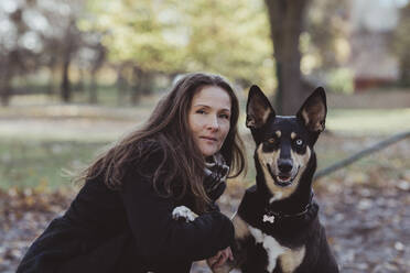 Seitenansicht Porträt einer lächelnden Frau mit Hund im Park - MASF19274