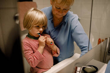 Großmutter mit Enkel beim Zähneputzen im Badezimmer zu Hause - MASF19326