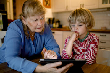 Junge sieht Großmutter mit digitalem Tablet an - MASF19331