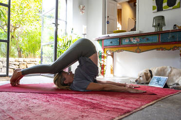 Frau, die drinnen auf dem roten Teppich Yoga übt. - ISF24237