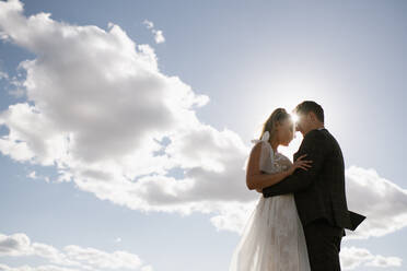 Bride and groom hold each other with sky background - ADSF00168