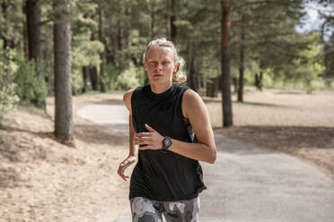 Junge blonde Frau joggt im Wald - VPIF02575