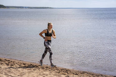 Junge Frau joggt am Strand - VPIF02577