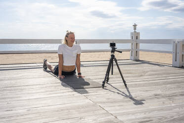 Young athletic woman during workout and video recording at beach - VPIF02586