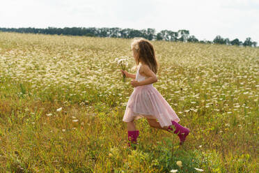 Kleines Mädchen läuft im Sommer durch ein Blumenfeld. - CAVF86776