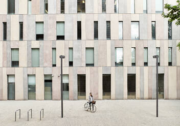 Businesswoman standing with bicycle on street outside office building - VEGF02457