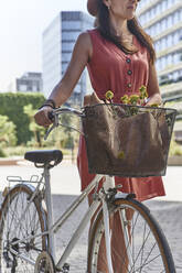 Woman standing with bicycle on city street - VEGF02487