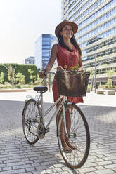 Happy woman standing with bicycle on city street - VEGF02488