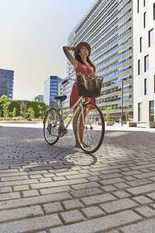 Nachdenkliche Frau steht mit Fahrrad auf der Straße - VEGF02489