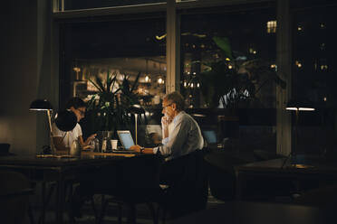 Male and female professionals working late in dark office at night - MASF19367