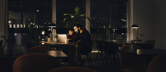 Confident male and female professionals working late together at creative office - MASF19375