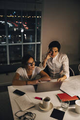 Hohe Winkel Ansicht von weiblichen und männlichen Unternehmern sitzen am Schreibtisch während der späten Nacht Sitzung im Büro - MASF19400