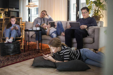 Family is using technologies in living room at modern home - MASF19427