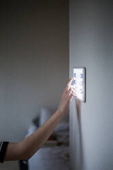 Ausgeschnittenes Bild eines Jungen, der ein digitales Tablet benutzt, das zu Hause an der Wand befestigt ist - MASF19443