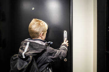 Boy unlocking combination security code on house door - MASF19460