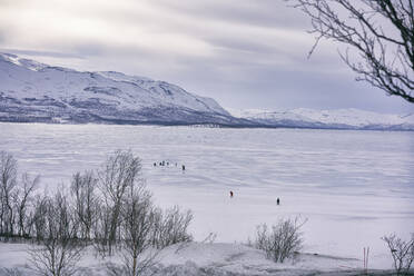 Blick über einen zugefrorenen See mit Menschen in der Ferne, Vasterbottens Lan, Schweden. - CUF55714