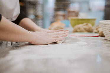 Bäckerin knetet Brotteig in einer Bäckerei - EBBF00369