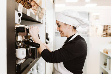 Fröhlicher Bäcker bereitet Kaffee in der Bäckerei zu - EBBF00392