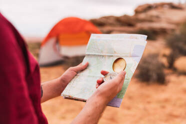 Crop Mann hält Karte und Retro-Kompass, während stehend auf unscharfen Hintergrund der majestätischen Wüste - ADSF00234