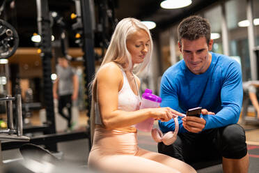 Man and woman using smartphone in gym - ADSF00264