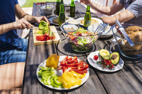 Nahaufnahme von Brunch auf einem Tisch mit jungen Freunden, die auf der Terrasse eines Gebäudes sitzen - JSMF01630