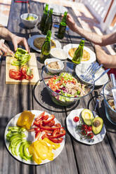 Brunch am Tisch mit männlichen Freunden auf der Terrasse eines Gebäudes an einem sonnigen Tag - JSMF01631